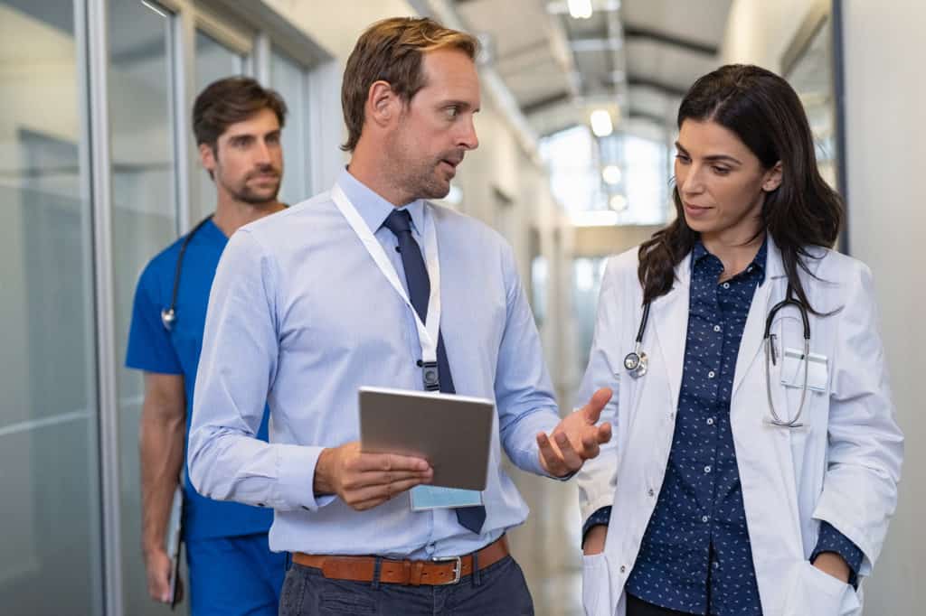 Man,And,Woman,Doctor,Having,A,Discussion,In,Hospital,Hallway.